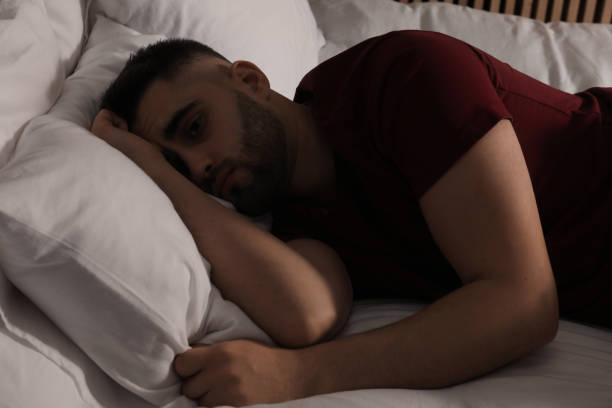 istock Sad man lying on bed at home 2164250683