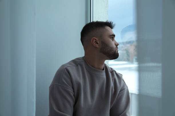 istock Sad man looking at window at home 2164250696