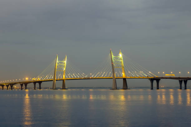 View of illuminated cable-stayed bridge over water surface in evening twilight