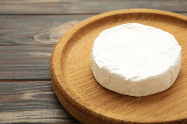 istock Camembert cheese on wooden plate on brown background. 2164256732