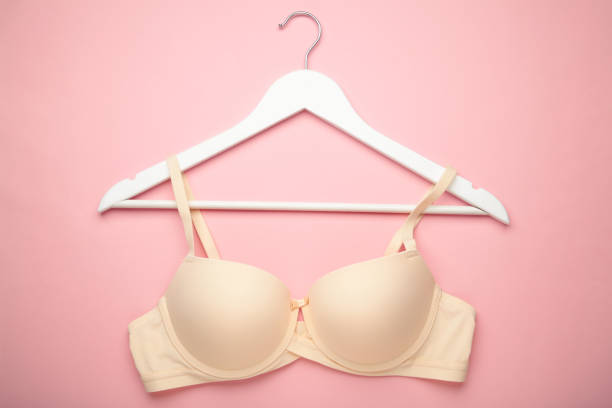 istock Female beige bra on a hanger on pink background. 2164257024