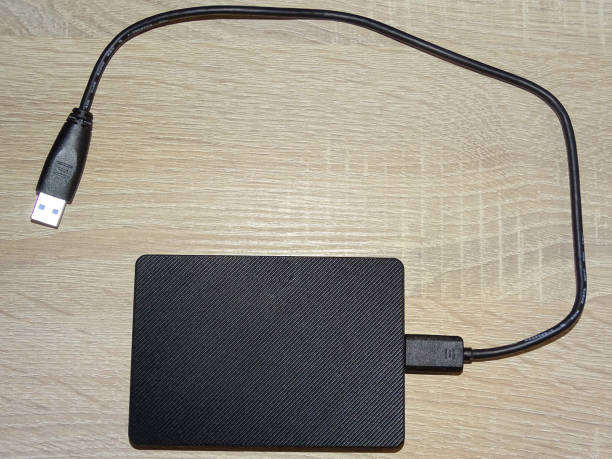 External hard drive with cable on a wooden background