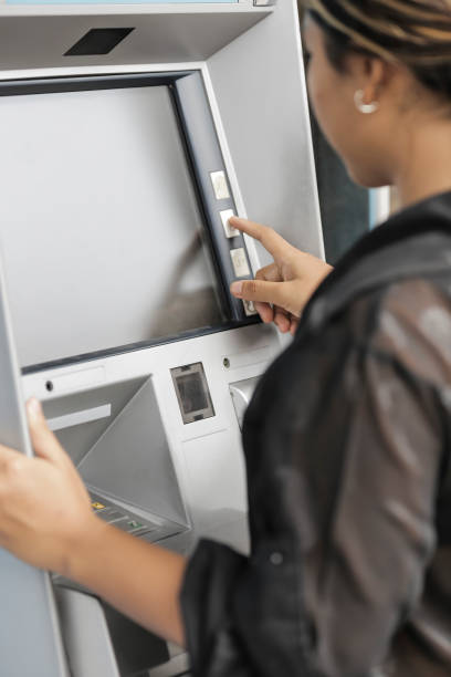 istock young woman withdrawing money with credit card from ATM machine typing pin code 2164258660