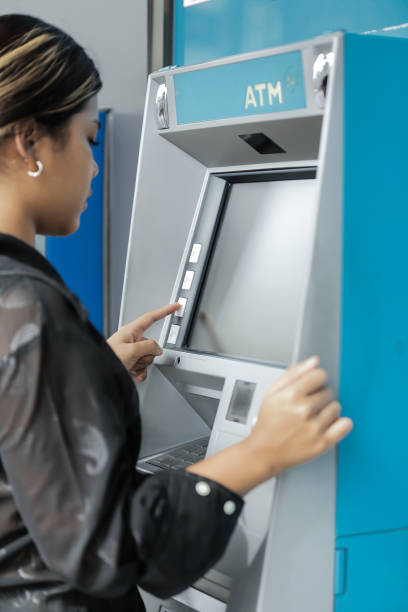 istock young woman withdrawing money with credit card from ATM machine typing pin code 2164258663
