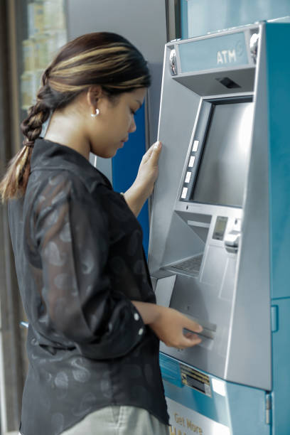 istock young woman withdrawing money with credit card from ATM machine typing pin code 2164258682