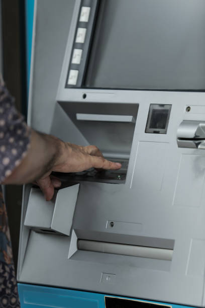 istock middle age man withdrawing money with credit card from ATM machine typing pin code 2164258732
