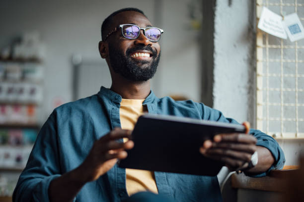 istock Smiling Man Holding Tablet in a Cozy Cafe Setting 2164260770