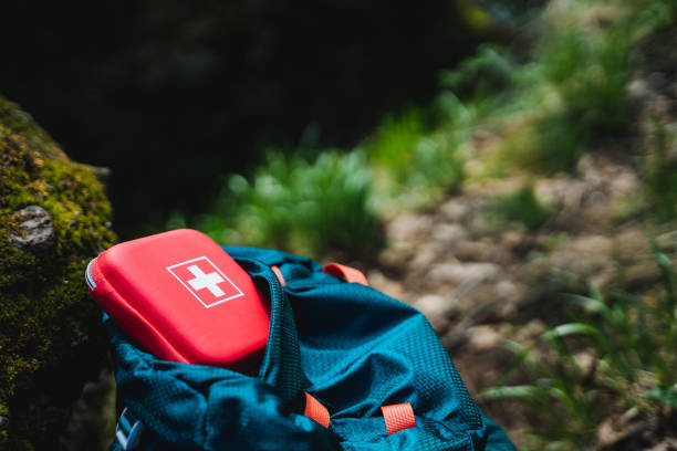 istock Electric blue backpack with red first aid kit on top in natural landscape 2164260950