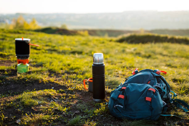 A backpack and a thermos are resting on the grass in a highland field, blending into the natural landscape of the outdoor recreation area