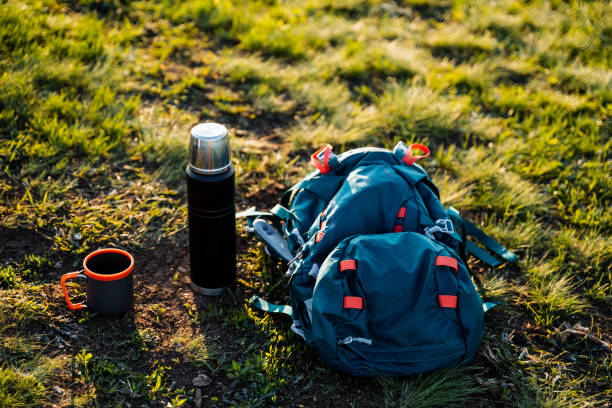 istock A backpack, thermos, and cup are on the grass in a natural landscape 2164260996