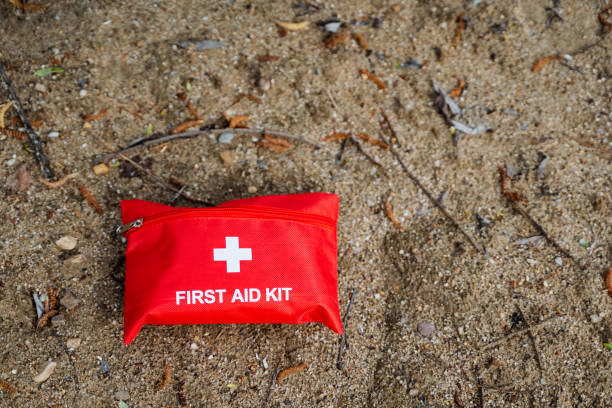 istock Red first aid kit on sandy surface with scattered leaves and twigs. Be prepared for emergencies in outdoor settings with essential medical supplies for safety and survival 2164261008
