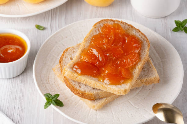 istock Apricot jam on bread in a white plate and a jar of apricot jam 2164262811