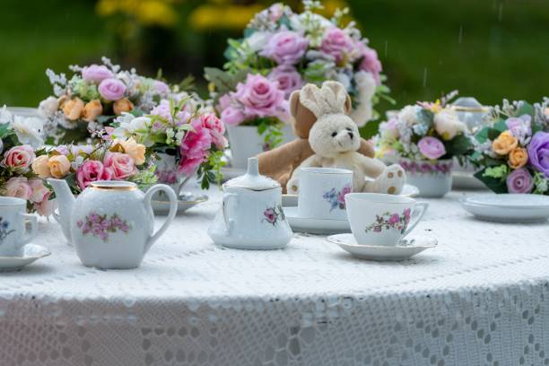 Charming garden tea party setting featuring elegant floral arrangements, fine china, and a cute stuffed bunny, creating a whimsical and inviting atmosphere.