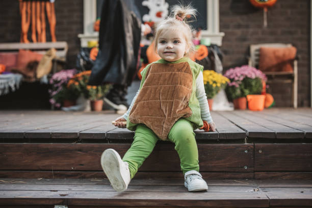 18 months old baby sitting on a purple garden chair and playing / discovering sunflowers, enjoying