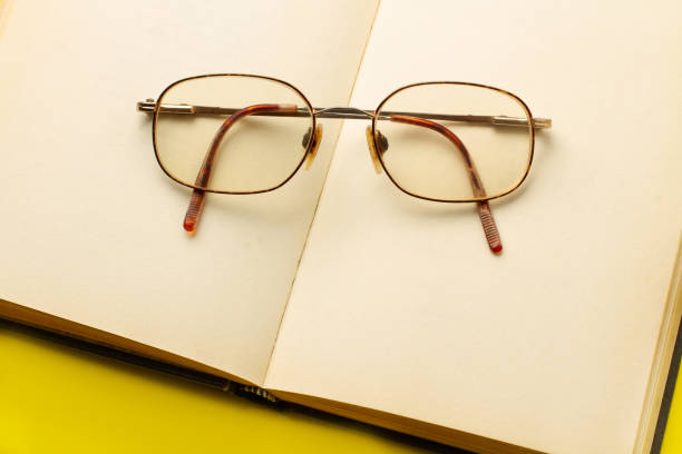 Eyeglasses on an open book on a yellow background in a top view