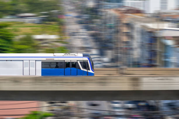 istock Speed modern commuter train, motion blur rides on a trestle bridge through buildings at height, side view 2164266941