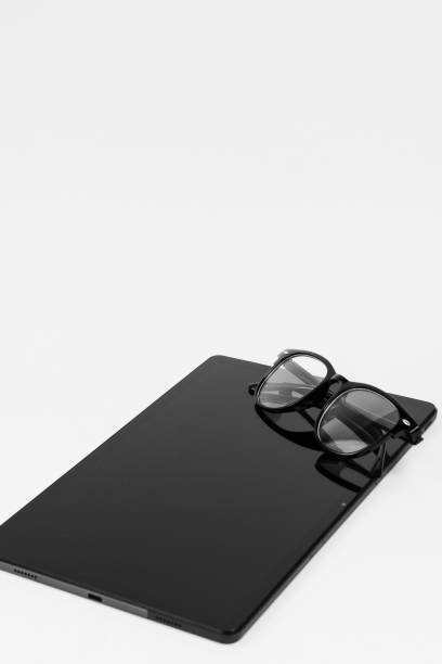 Modern glasses and Notebook on white background. Stylish glasses in black frames, Black glasses arranged on tablet, tablet and glasses on white background, lifestyle,