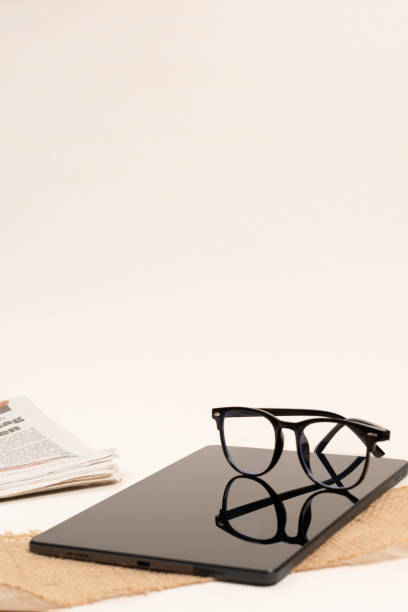 Modern glasses and Notebook on white background. Stylish glasses in black frames, Black glasses arranged on tablet, tablet and glasses on white background, lifestyle, newspaper and tablet