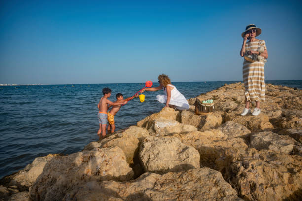 Family exploring rocky beach area on a sunny day