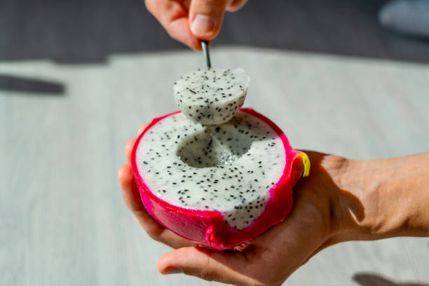 istock Man holds a spoon with his hand, eats a dragon fruit, beautifully pulls out round pieces, slices of fruit. 2164270689
