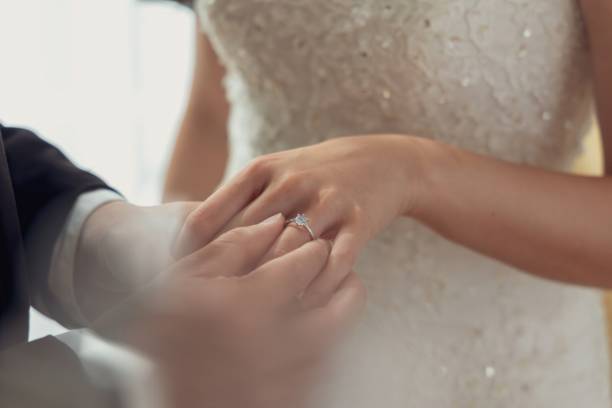 istock A groom places a wedding ring on his bride's finger during their wedding ceremony. 2164276432