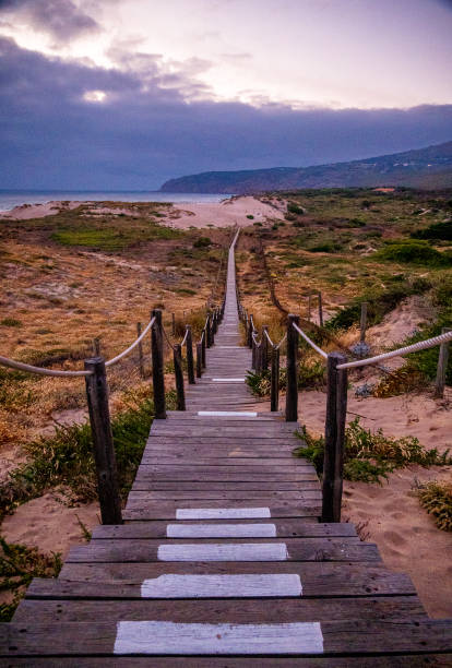 Brown stairs leading from the beach to the sea, on a cloudy day