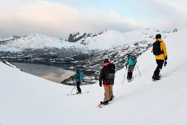 istock Four skiers and splitboarders stand on a snow-covered hill and look down at a small river flowing at the foot of the mountains 2164280689