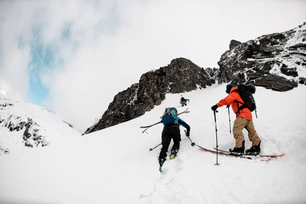 istock Three skiers climb a mountain, overcoming a difficult section with a steep climb 2164283759