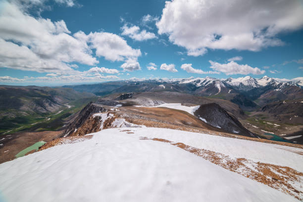 istock Scenic panoramic top view along large wide mountain range with snowfield and freshly fallen snow in center separating two green alpine valleys with turquoise lakes. High snowy mountains in far away. 2164285135