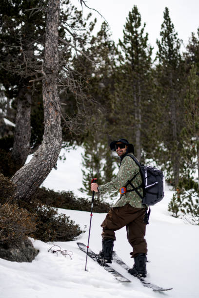 istock Happy smiling skier with backpack standing on skis between trees and looking back and to the side 2164286076