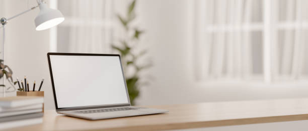 istock A laptop computer with a white-screen mockup and decor on a wooden tabletop in a bright room. 2164294335