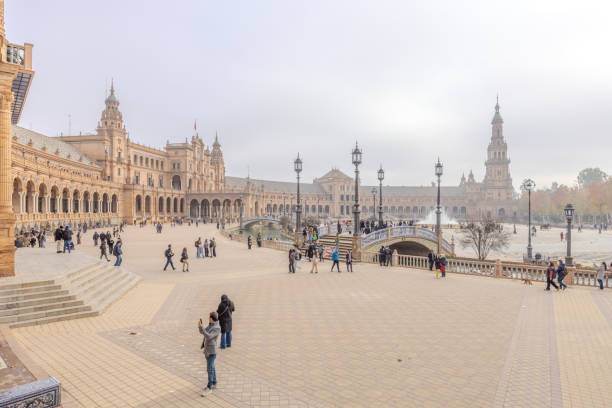 Seville, Spain - December 31, 2023:  Many visitors seen outside the majestic Plaza de Espana in a foggy afternoon on New Year Eve 2023.  HDR encoded.
