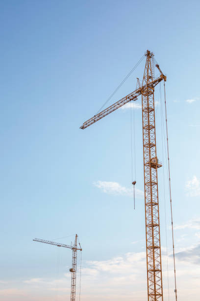 istock Two tower cranes on the evening blue sky background, vertical photo. 2164299368
