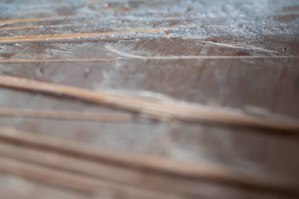 Stack of wooden planks with a shallow depth of field creates an abstract pattern. The wood's texture and grain are visible, highlighting the natural beauty of the material