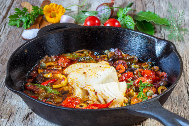 Mediterranean baked white fish fillet on iron pan.