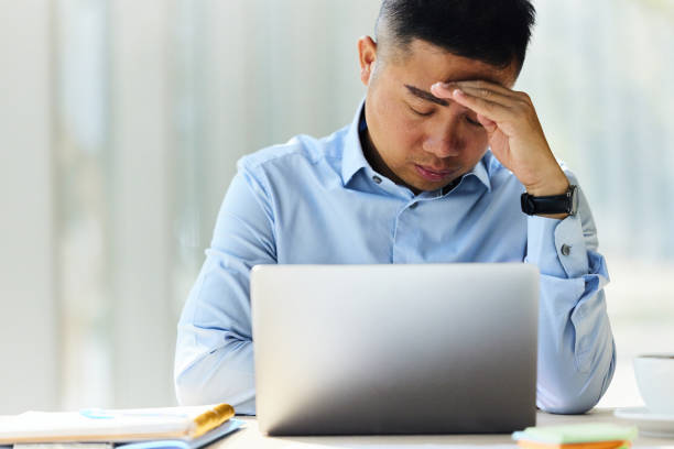 istock Chinese businessman having a headache while working on laptop in the office. 2164304237