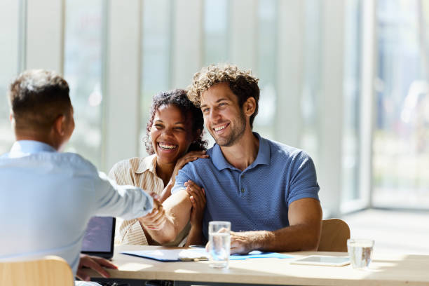 istock Happy couple shaking hands with their agent in the office. 2164304663
