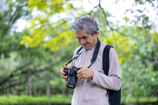 istock Asian senior man is trekking in the forest while using camera to take memorable photo for elder exercise outdoor and nature environment therapy concept 2164307175