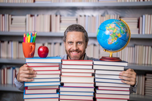 istock Man with books in library. Knowledge and education. school library. Teachers day. Teacher in school classroom. teacher with book in library classroom. Hispanic teacher in college. Education system 2164309497