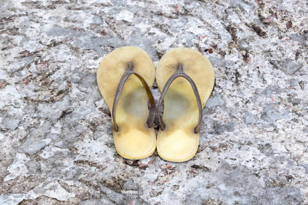 A pair of old sandals on the cement floor.