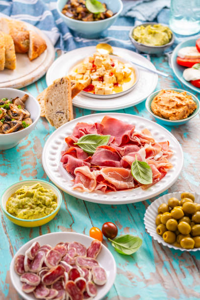 istock Picnic table with assorted appetizers, raw vegetables, cheese, dips, baguette and pastrami and serrano platter 2164311234