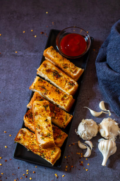 istock delicious garlic bread on a black background, serve with tomato sauce. selective focus. 2164312483