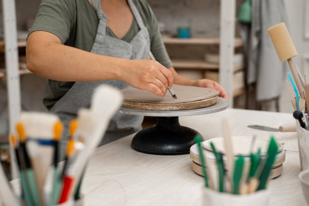 istock Using a sharp pottery carving knife to cut out a perfect round shape from clay. Ceramics class. Modeling clay into a round form. 2164313857
