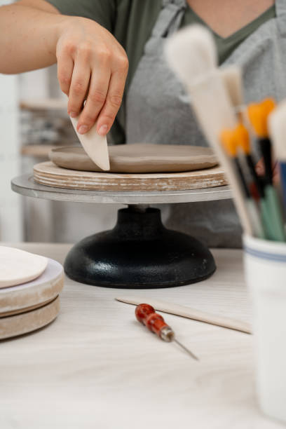 istock Crafting smooth angle conversion and textured ribs with a clay pottery scrapper. Girl is using a pottery scrapper to smooth the edges of a clay product. 2164313883