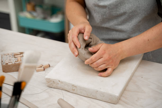 istock Wedging the clay before starting making a pottery project to create proper consistency. Removing air bubbles from clay before modeling to avoid the ruination of a ceramic product. 2164314033