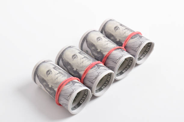istock A row of rolled hundred dollar bills with rubber bands 2164316418
