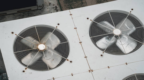 Air conditioner compressor on a building's rooftop, accompanied by industrial air conditioning units and ventilation systems.