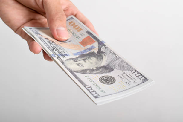 istock Man hand reaching out dollar bill. US $100 banknote 2164322353