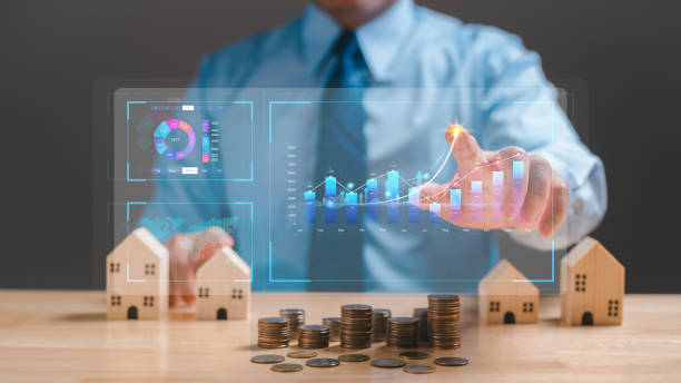 istock A businessman is pointing at a graph on a computer screen while holding a pile of coins. Coins are arranged in a pyramid shape, and man is wearing a blue shirt and a tie. Concept of financial success 2164322468