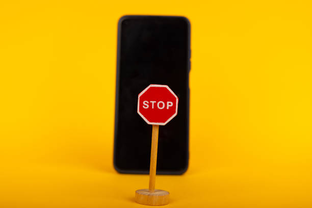 istock Toy Stop Sign and Smartphone on Yellow Background 2164323950